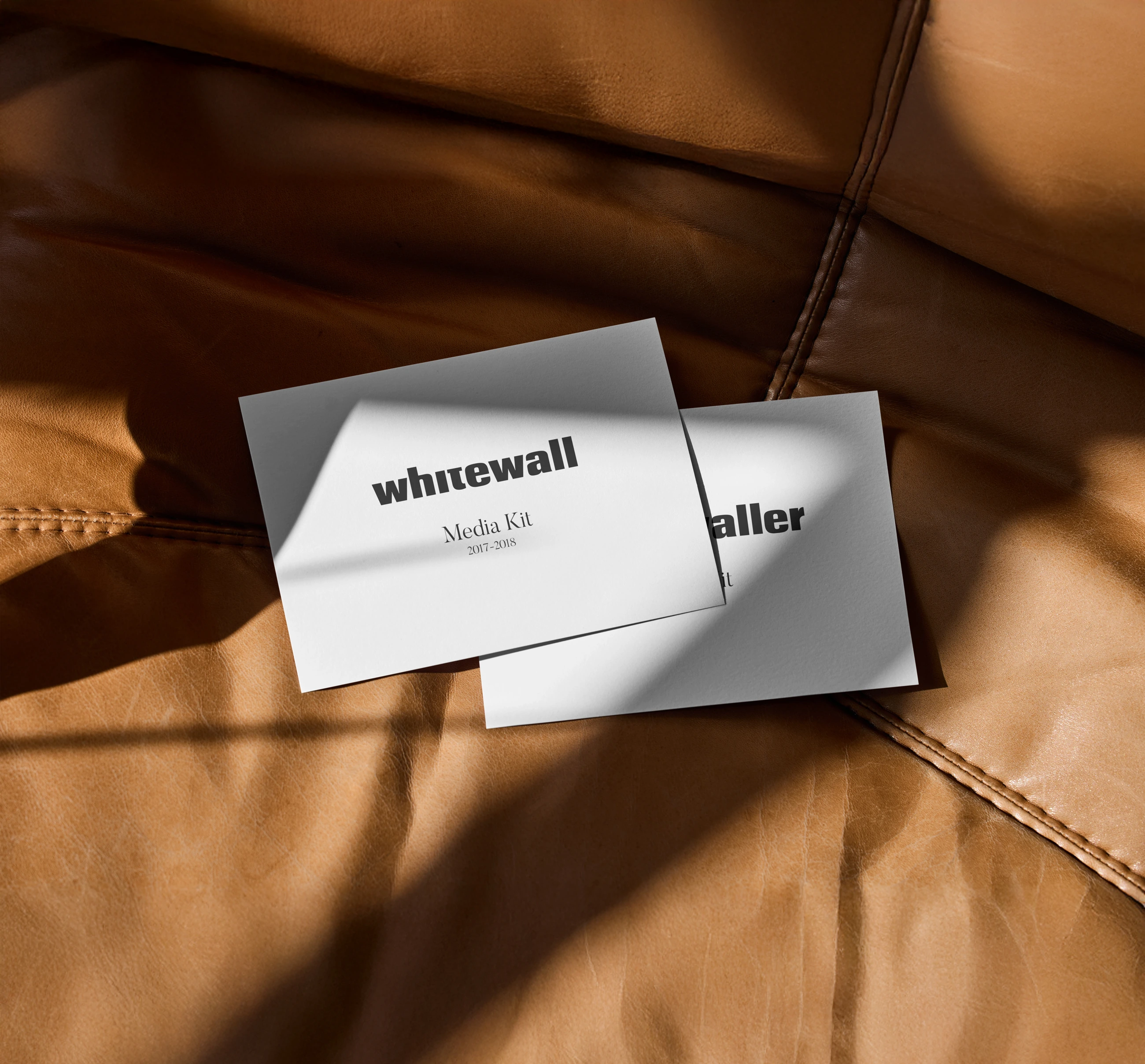 Whitewall and Whitewaller media kit covers resting on warm brown leather